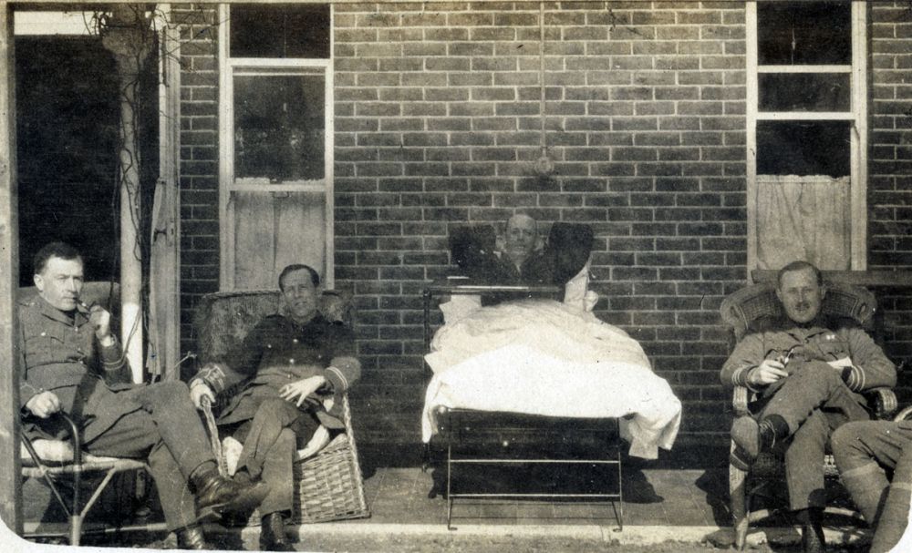 Three medical officers by a patient in a hospital bed at the Forest Park Hotel, Brockenhurst, England.